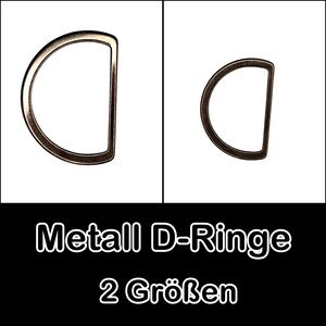 Könnte beinhalten: Zwei Metall-D-Ringe in verschiedenen Größen. Der größere D-Ring befindet sich links und der kleinere rechts. Beide Ringe sind silberfarben.