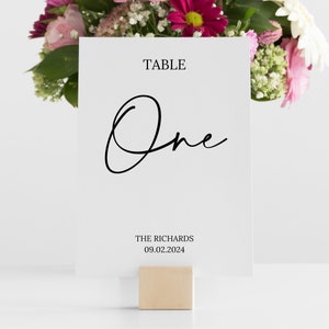 May include: White table number card with black calligraphy that says "Table One" and the text "THE RICHARDS 09.02.2024"