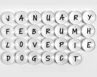 以下が含まれることがあります： 黒い文字で「JANUARY FEBRUARY LOVE DOGS」と「MARCH APRIL PIE  ECT」と綴られた白い丸いタイル。