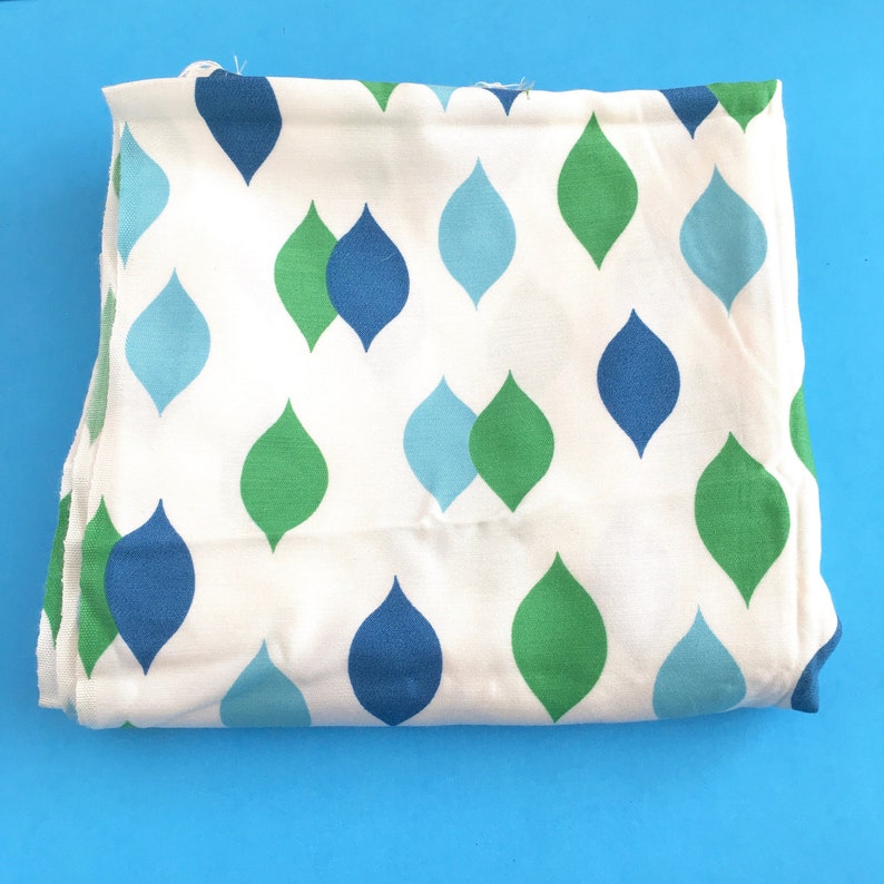 May include: White fabric with a repeating pattern of blue, green, and light blue teardrop shapes.