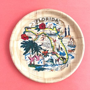 May include: Round bamboo tray with a colorful map of Florida, featuring illustrations of palm trees, flamingos, and various landmarks. The word "FLORIDA" is printed across the top.