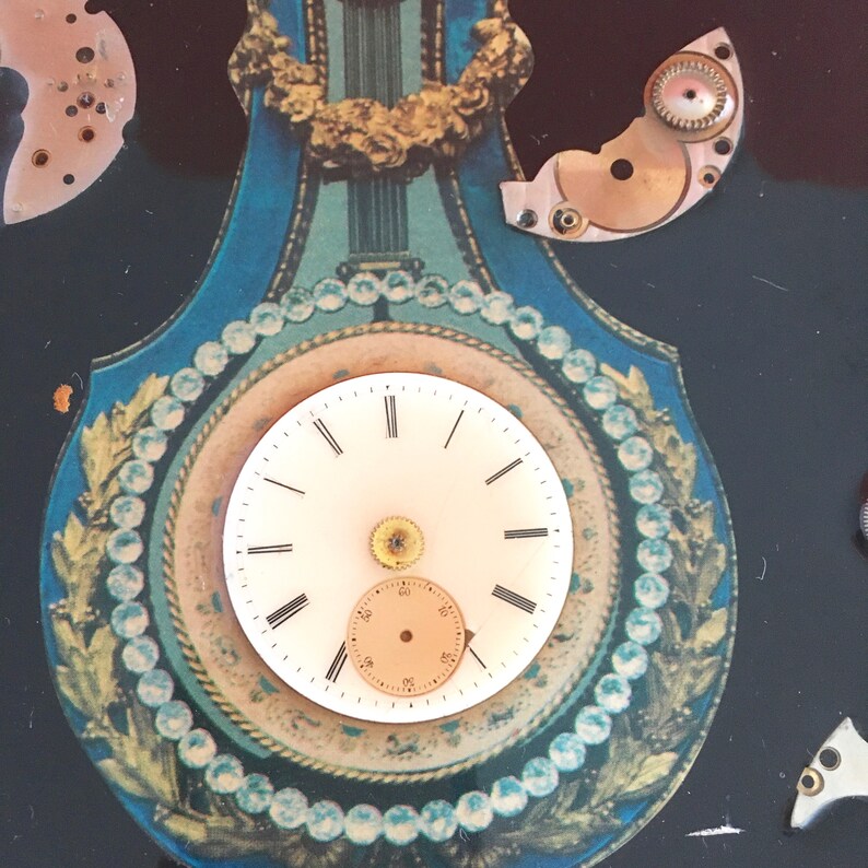 May include: A vintage clock face with Roman numerals and a decorative gold trim. The clock is surrounded by a blue and gold design with a pearl-like border.