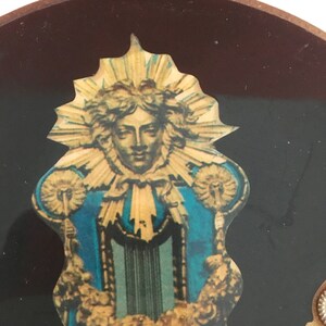 May include: A vintage religious image of a person with a halo and a blue robe. The image is surrounded by a gold frame with a sunburst design.