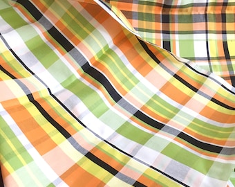 May include: A fabric with a plaid pattern in orange, green, yellow, black, and white.