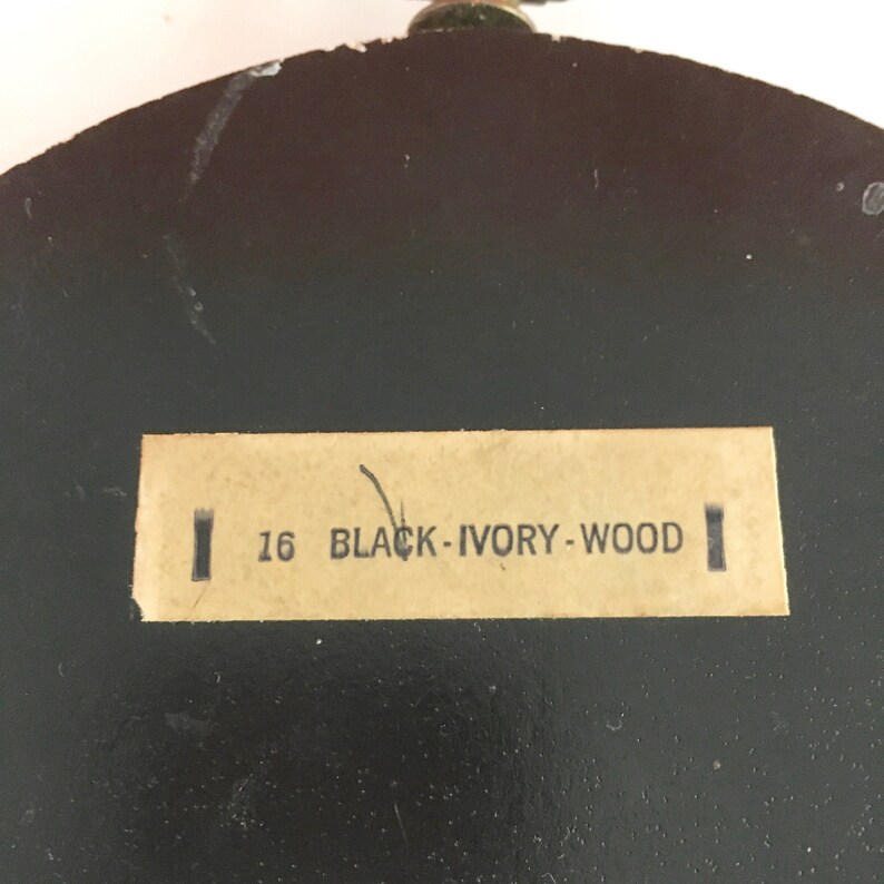 May include: Close-up of a brown wooden object with a label that reads "16 BLACK - IVORY - WOOD".