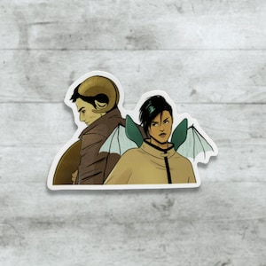 May include: A sticker featuring two figures from a fantasy setting. One figure has ram horns and a brown coat, while the other has black hair and green bat-like wings, wearing a tan jacket.