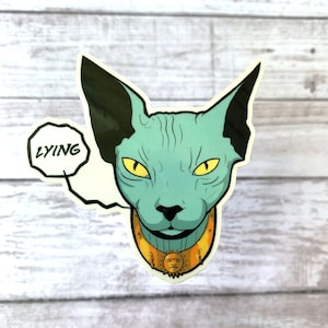 May include: A blue Sphynx cat with yellow eyes wearing a gold collar with a sun face design. The cat is looking directly at the viewer and has a speech bubble above its head that says "LYING".