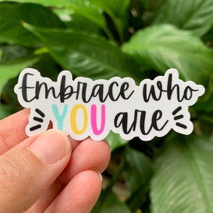 May include: White sticker with the text "Embrace who =YOU are=" in black script. The word "YOU" is in colorful letters with a yellow outline.