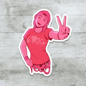 K&ouml;nnte beinhalten: Ein rosa Sticker mit einer Comic-Frau mit rosa Haaren und einem rosa Shirt. Sie zeigt mit ihrer rechten Hand ein Peace-Zeichen. Der Bauch der Frau besteht aus rosa W&uuml;rmern.