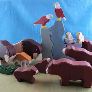 May include: A set of wooden animal figurines, including a brown bear, a bison, and a bald eagle. The figurines are painted in realistic colors and have a hand-crafted look. The set is perfect for imaginative play or as a decorative piece.