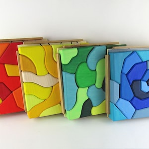 May include: Five wooden puzzle boxes with colourful geometric patterns. Each box has a different colour scheme, including red, yellow, green, blue, and natural wood.
