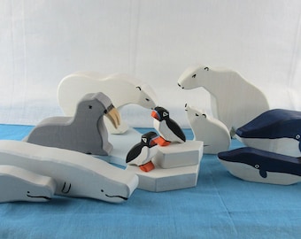 May include: A set of wooden arctic animal figurines, including a polar bear, walrus, beluga whales, and puffins. The figurines are painted in realistic colors and are perfect for imaginative play.