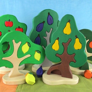May include: A set of five wooden toy trees with different colored fruits. The trees are green, brown, and gray. The fruits are red apples, yellow lemons, yellow pears, purple plums, and orange oranges.