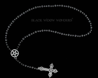 May include: A silver-colored necklace with a pentagram pendant and a decorative cross pendant. The necklace is made of small, round beads and features the text "BLACK WIDOW WONDERS" on a black background.