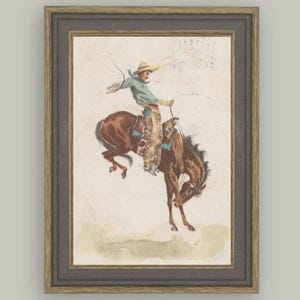 Vintage Western cowboy art print titled “In the Saddle” featuring a bronc rider on a bucking horse. Antique postcard illustration perfect for rustic ranch décor, cowboy wall art, Western nursery themes, or masculine home office styling. High-resolution vintage reproduction ideal for collectors.