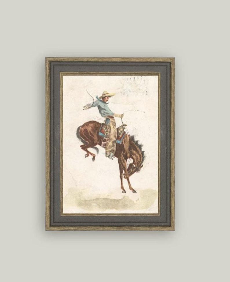 Framed reproduction of vintage cowboy and bucking horse artwork “In the Saddle.” Rustic Western wall décor for ranch homes, masculine office styling, cowboy nursery themes, and Americana art lovers. High-quality print of antique illustration
