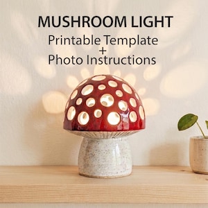 May include: A mushroom-shaped lamp with a glossy red cap featuring circular cutouts and a speckled white base. The text MUSHROOM LIGHT Printable Template + Photo Instructions is displayed above the lamp, which emits a warm glow through the holes.