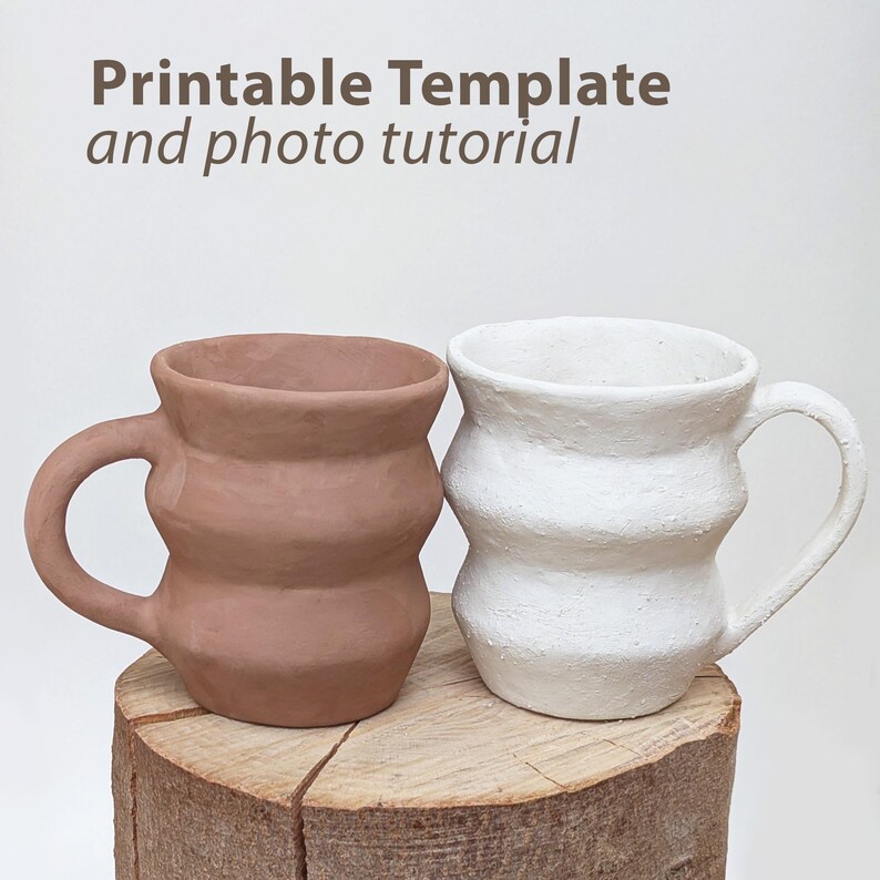 May include: Two handmade ceramic mugs, one in a terracotta color and the other in white, sit side-by-side on a wooden surface. The mugs have a unique, wavy design and attached handles. The text "Printable Template and photo tutorial" is at the top.