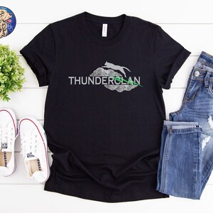 May include: Black t-shirt with a white graphic of a cat jumping over a cloud with the text "THUNDERCLAN" in green.