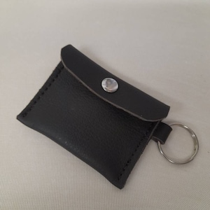 Portamonete piccolo in pelle marrone, porta auricolari. Con portachiavi e borchia color argento.
