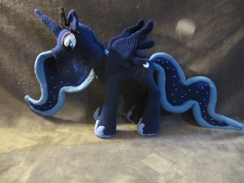 May include: A crocheted plush toy of Princess Luna from My Little Pony: Friendship is Magic. The toy is blue with a light blue mane and tail, and has a crescent moon symbol on its flank.