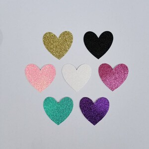 May include: Seven glitter heart shapes in various colors, including gold, black, pink, white, purple, and teal.