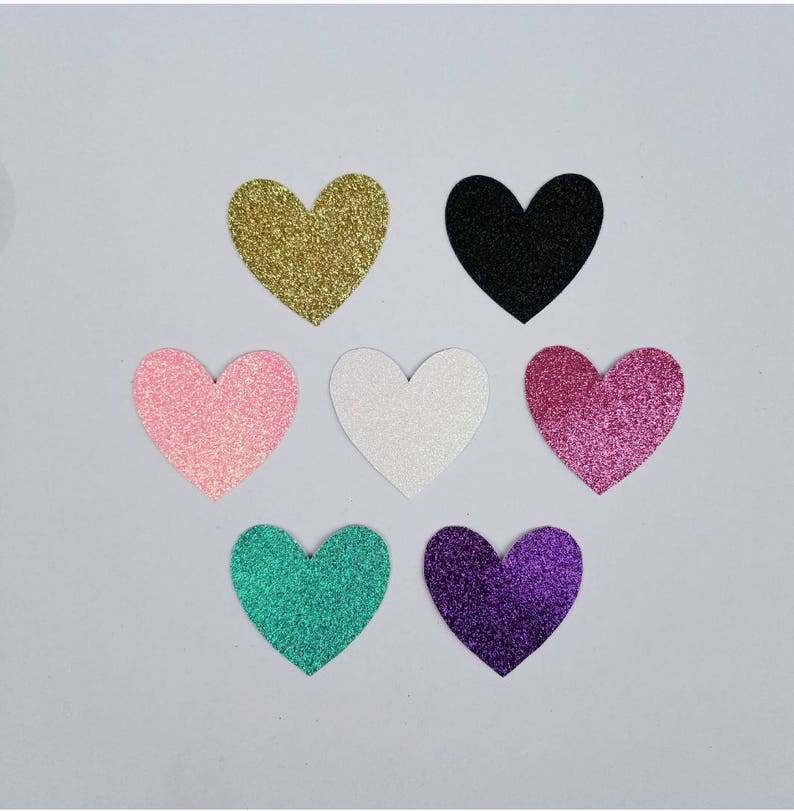 May include: Seven glitter heart shapes in various colors, including gold, black, pink, white, purple, and teal.