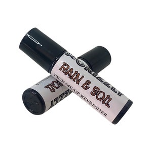 May include: Two black roll-on bottles with white labels. The label on the top bottle reads "GRIZZLY RAIN & SOIL PICK-ME-UP REFRESHER". The label on the bottom bottle reads "GRIZZLY MO", but the rest of the text is obscured.