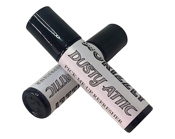 May include: Two roll-on bottles of "Dusty Attic Pick-Me-Up Refresher" with black caps and white labels. The labels feature the product name in a stylized font. The bottles are positioned at an angle, overlapping each other.