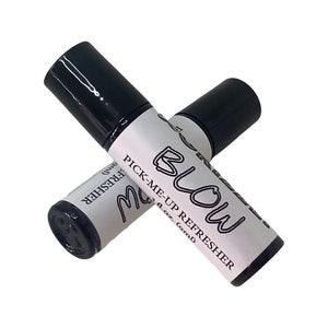 May include: Two black rollerball bottles with white labels. The label on the top bottle reads "BLOW PICK-ME-UP REFRESHER 1/2 oz. (omD)". The label on the bottom bottle reads "FRESHER omD".