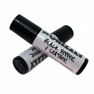 Pode incluir: Duas garrafas pretas de roll-on com rótulos brancos. O rótulo na garrafa superior diz "GRIZZLY BLACK PEPPER & LEATHER PICK-ME-UP REFRESHER". O rótulo na garrafa inferior diz "GRIZZLY BLACK PEPPER".