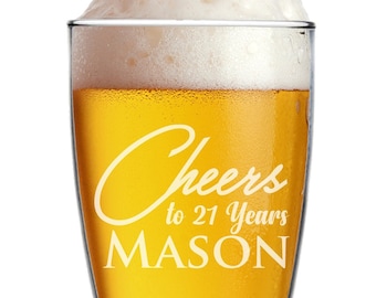 Może przedstawiać: Wysoki, przezroczysty szklany kufel do piwa z białym napisem "Cheers to 21 Years MASON". Kufel jest wypełniony złotym piwem i zwieńczony białą pianą.