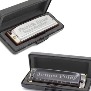 May include: A silver harmonica with a black case. The harmonica is engraved with the text "Patrick Sims Happy Birthday!" The case is open and the harmonica is inside.