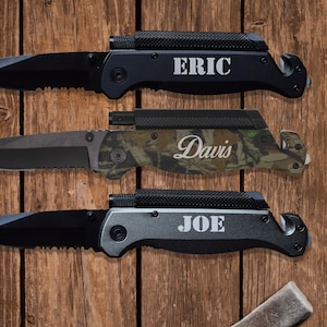 May include: Three black pocket knives with a safety feature and a built-in seatbelt cutter. The knives are engraved with the names "Eric", "Davis", and "Joe".