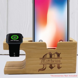 Może przedstawiać: Drewniany stojak do ładowania telefonu i zegarka z personalizowanym monogramem. Stojak jest grawerowany nazwiskiem "Matthews" i ozdobną literą "M". Stojak ma szczelinę na telefon i podwyższoną platformę na zegarek.