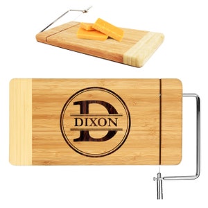 May include: A personalized bamboo cheese board with a wire cheese cutter. The board has a circle with the letter "D" and the name "DIXON" engraved on it.