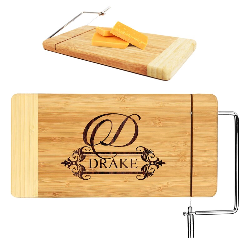 May include: A personalized bamboo cheese board with a wire cheese cutter. The board has a decorative engraved design with the letter "D" and the name "DRAKE".