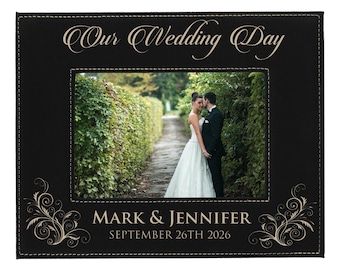 May include: Black photo frame with the text "Our Wedding Day" in elegant script. The frame features a photo of a couple on their wedding day. The names "Mark & Jennifer" and the date "September 26th 2026" are displayed at the bottom.