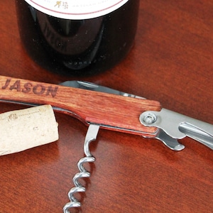Peut inclure: Un tire-bouchon en bois et acier inoxydable avec un tire-bouchon, un ouvre-bouteille et un coupe-capsule. Le manche est grav&eacute; du nom "JASON".