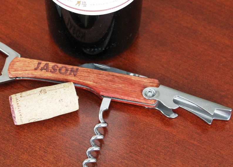 Peut inclure: Un tire-bouchon en bois et acier inoxydable avec un tire-bouchon, un ouvre-bouteille et un coupe-capsule. Le manche est grav&eacute; du nom "JASON".