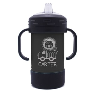 May include: Black and grey insulated toddler sippy cup with two handles. The cup features a lion riding in a dumper truck with the name "CARTER" printed below.