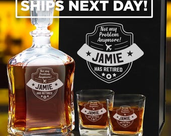 May include: A clear glass decanter and two matching whiskey glasses filled with amber liquid. Each piece features an etched emblem with an airplane icon and the text: Not my Problem Anymore! JAMIE HAS RETIRED. A black gift box is positioned behind.