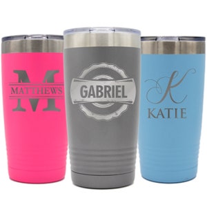 Pode incluir: Tr&ecirc;s canecas isoladas em rosa, cinza e azul. A caneca rosa tem o nome "MATTHEWS" com uma grande inicial "M". A caneca cinza tem o nome "GABRIEL" em uma faixa. A caneca azul tem o nome "KATIE" com uma inicial "K" em it&aacute;lico.