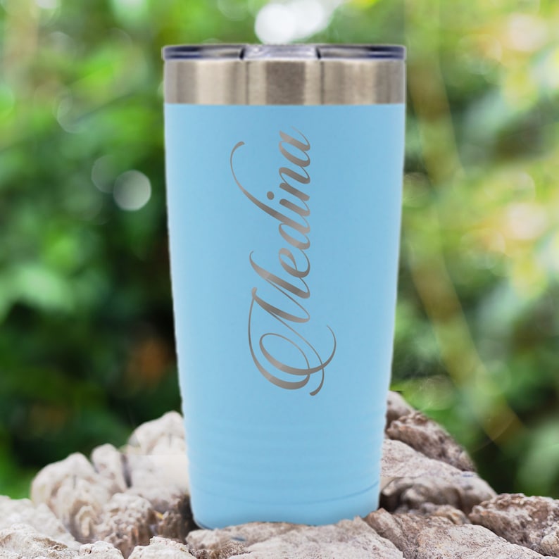 May include: A light blue stainless steel tumbler with the name "Medina" engraved on the side.