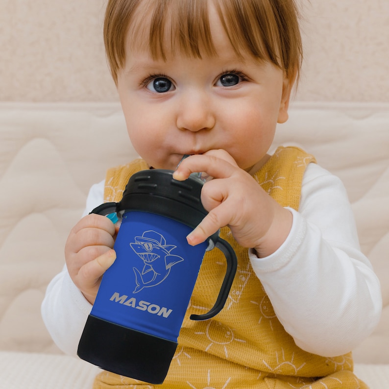 May include: A blue and black insulated toddler sippy cup with a straw, a shark graphic, and the name "MASON" engraved on the side.