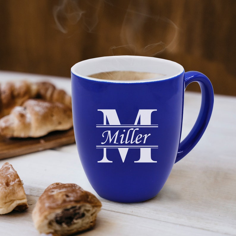 Pu&ograve; includere: Una tazza in ceramica blu intenso con interno bianco, caratterizzata da una grande lettera M bianca con il nome Miller stampato in corsivo bianco al centro della lettera. La tazza &egrave; riempita con una bevanda calda che emette vapore visibile.