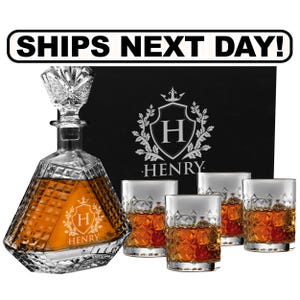 May include: A clear glass decanter with a diamond-cut pattern and a matching stopper, accompanied by three matching whiskey glasses filled with amber liquid. The decanter features an etched crest with the letter H and the name HENRY.