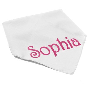 May include: A white triangular bandana featuring the name Sophia printed in a bold, dark pink font across the center. The fabric has a smooth texture and clean, finished edges, presenting a simple design with the name clearly visible in pink.