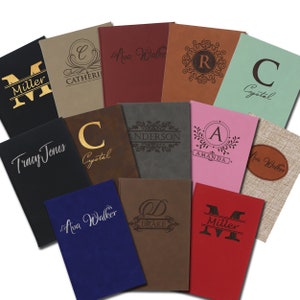 May include: A collection of personalized notebooks in various colors, including black, red, and blue. Each notebook features custom engraved text, such as names and initials, and decorative designs. The notebooks are arranged in a visually appealing display.