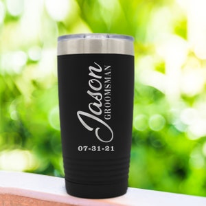 May include: Black stainless steel tumbler with a white engraved design. The tumbler has the name "Jason" and the word "Groomsman" with the date "07-31-21".